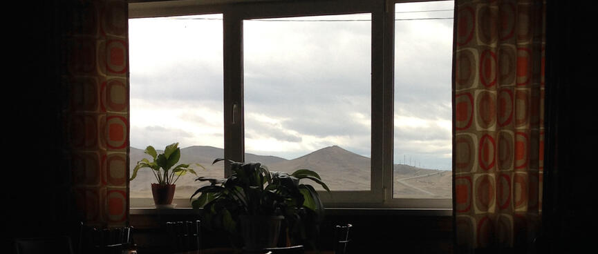 Mountains visible through the window of a dark room.