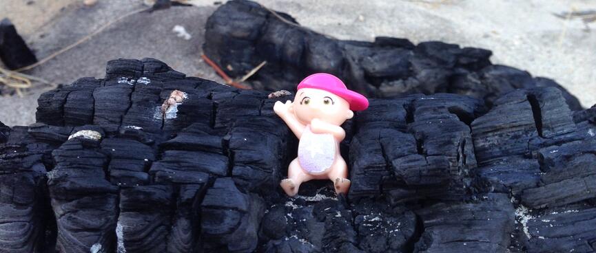 A small plastic doll wears a pink cap.