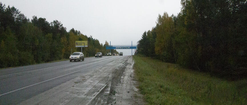 A blue Irkutsk sign straddles the highway at the city limits.