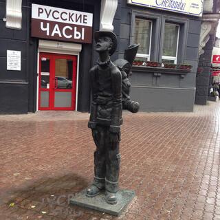 A metal statue of a boy wearing a hat and a backpack.
