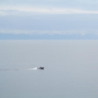 A small speedboat leaves a splashy white wake.