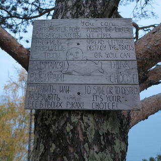 A wooden sign implores campers to take care of their surroundings.