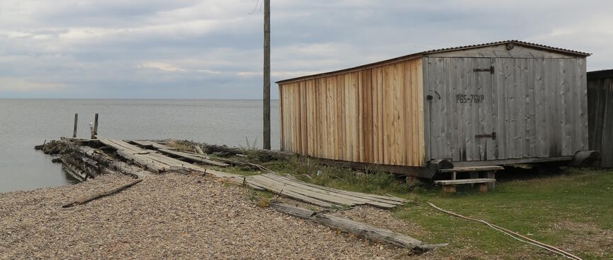 A small wooden jetty next to a boat house.
