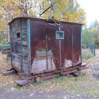An small railway carriage sits on top of log skids.