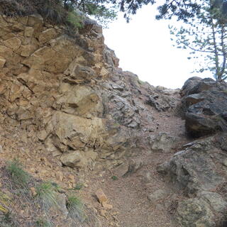 A trailside rock face splinters into small rocks.
